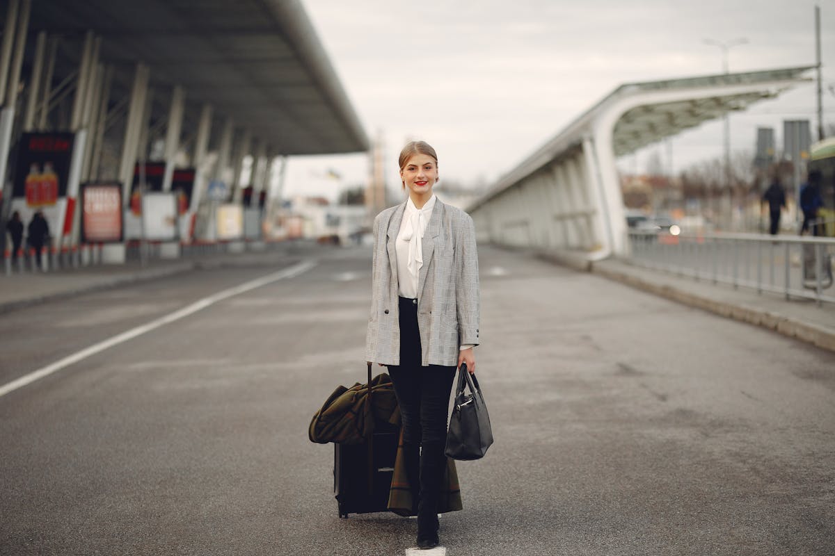 Happy female traveler walking on airport street with luggage