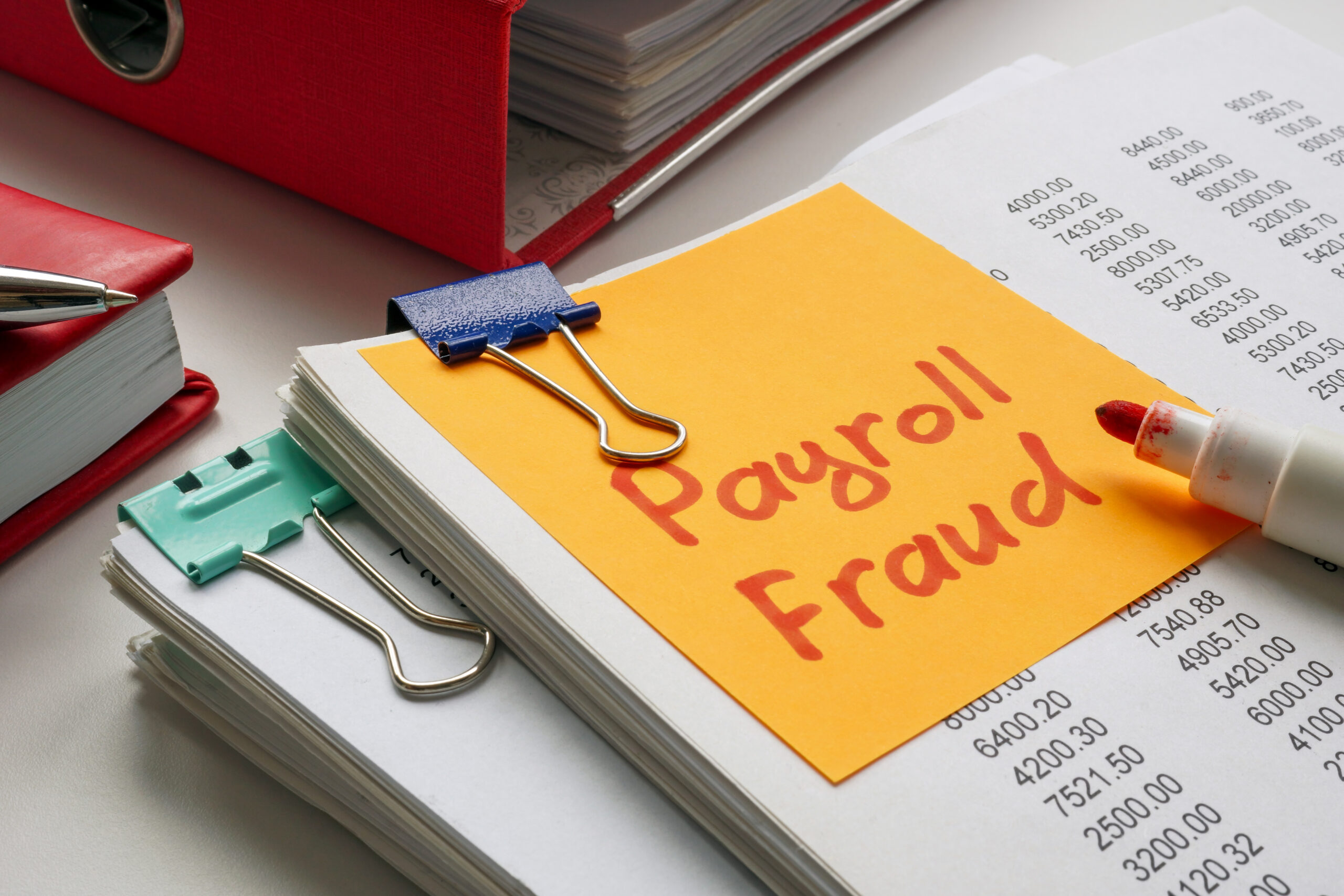 Stack of documents with note saying payroll fraud.