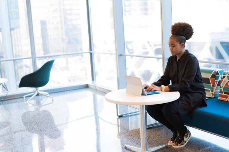 African American woman typing on a laptop in a bright, modern office space.