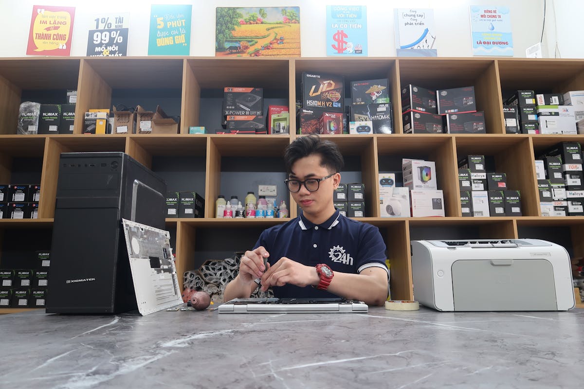 Young technician fixing a computer in a modern electronics store setting.